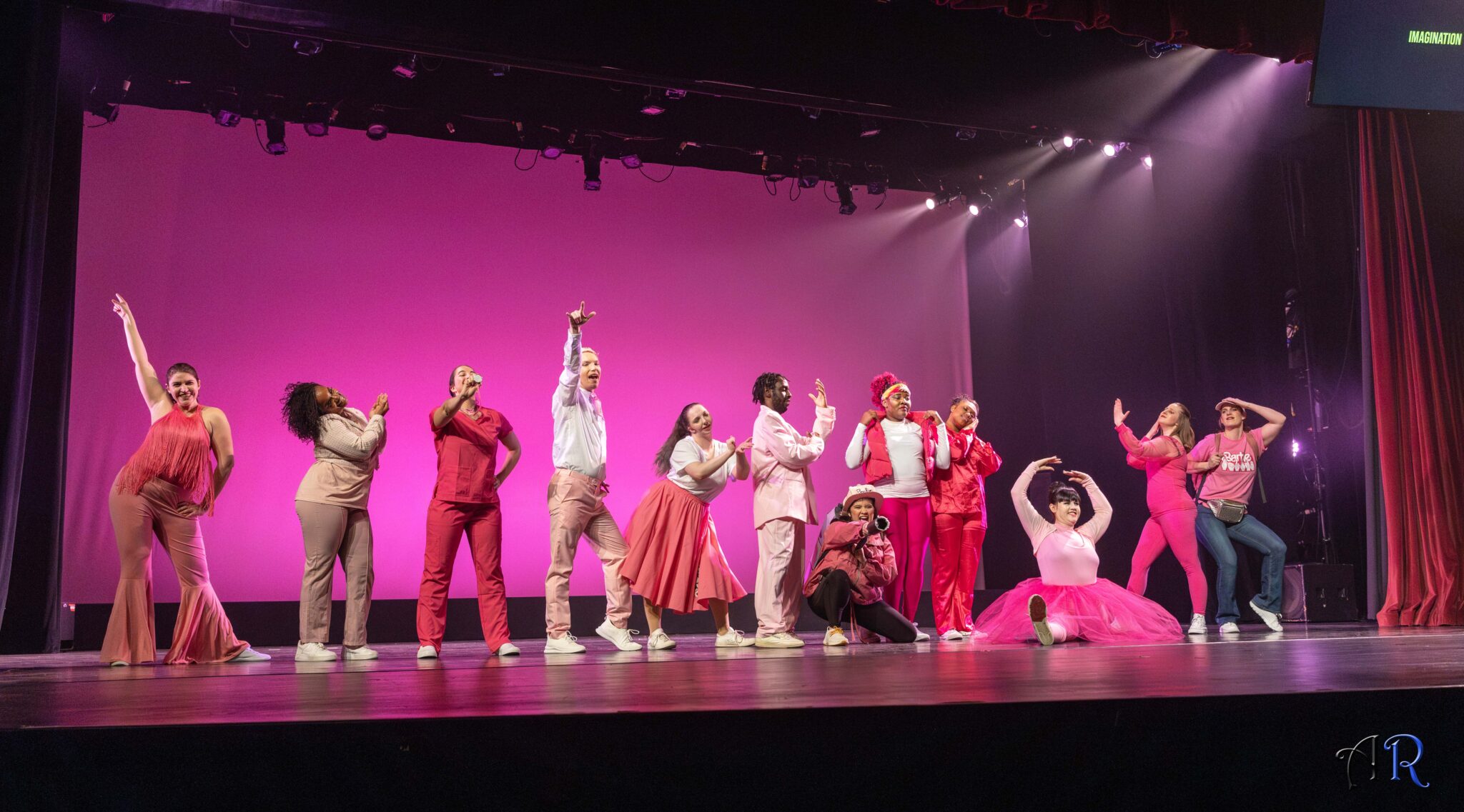 Line of dancers all wearing different interpretations of barbie’s costumes