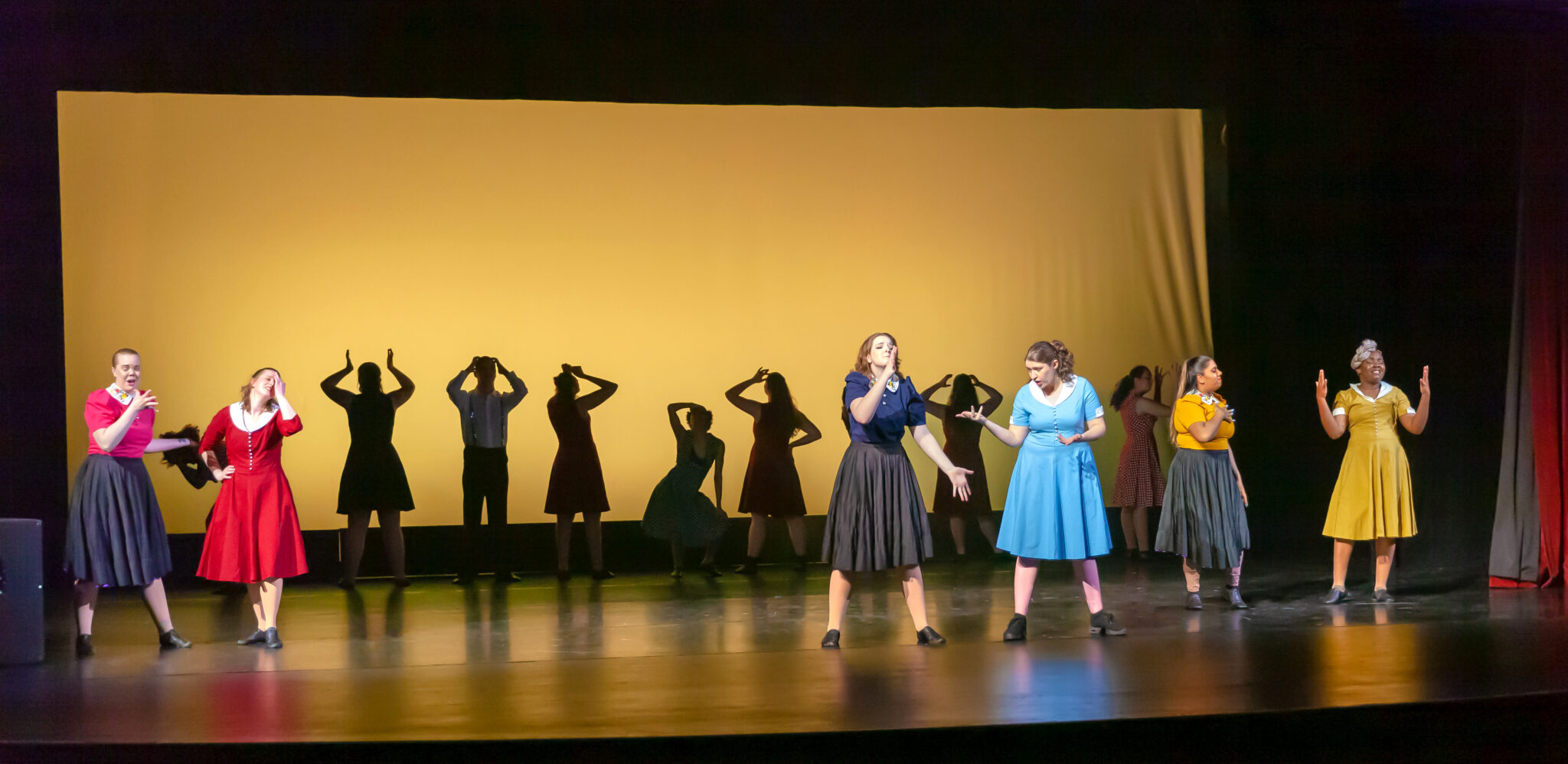 Yellow background, 3 pairs of 2 dancers in blue, green red and the rest are outlines in the back