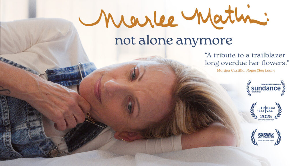 A horizontal-aligned poster for film Marlee Matlin: Not Alone Anymore. Marlee Matlin is lying down on a bed with white sheets, with the lower half of her body offscreen to the left. She is wearing overalls and a white shirt. Above her head is the film title. To the right of her head is text: "'A tribute to a trailblazer long overdue her flowers.' / Monica Castillo, RogerEbert.com". Below the text are laurels from Sundance Film Festival, Tribeca Film Festival, and SXSW.