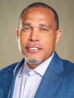 Man with goatee wears a white button down and a blue jacket