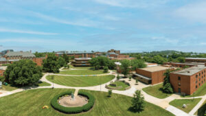 A panoramic perspective looking down on the Gallaudet mall. The grassy open area of the mall spans from the bottom, with the horizon converging on a large layered building slightly off left of center.