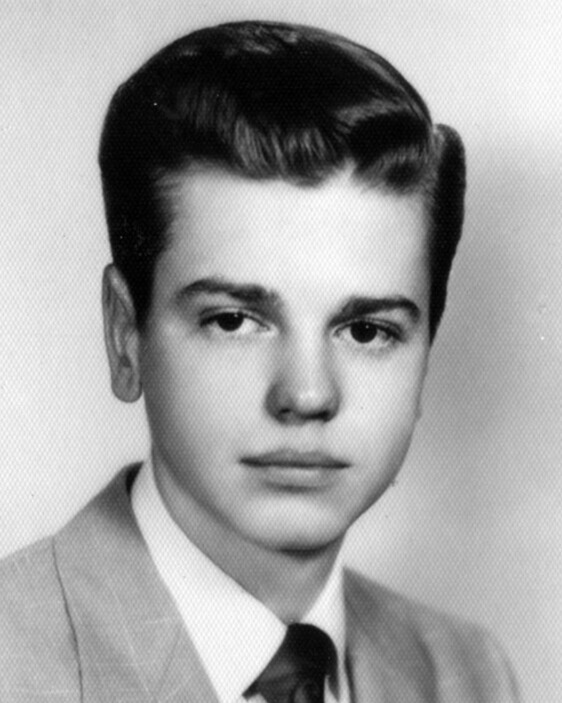 A old black-and-white photo of a young college student. They have styled dark hair and a gray suit.