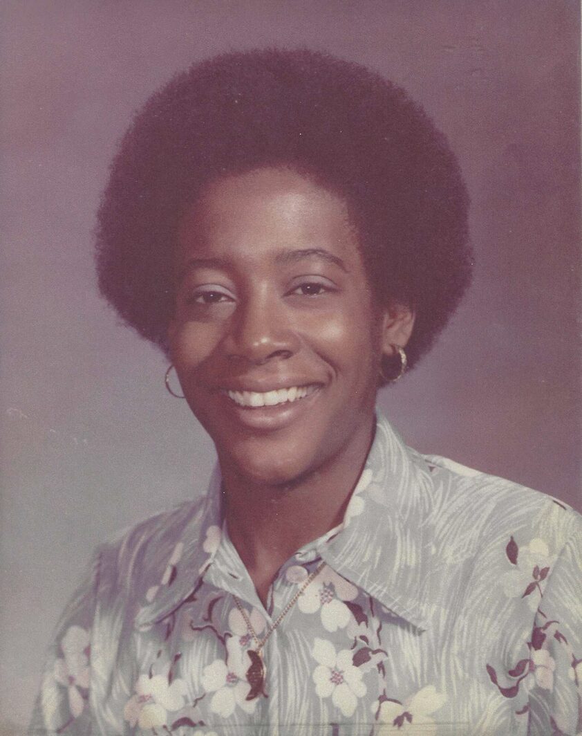 A dated school photo showing a young woman with short hair wearing a button-down shirt